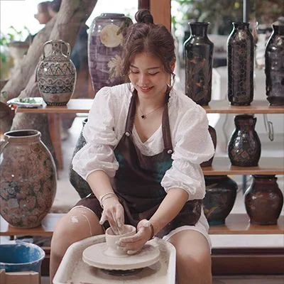 Học viên mỉm cười khi tạo hình đất sét trên bàn xoay